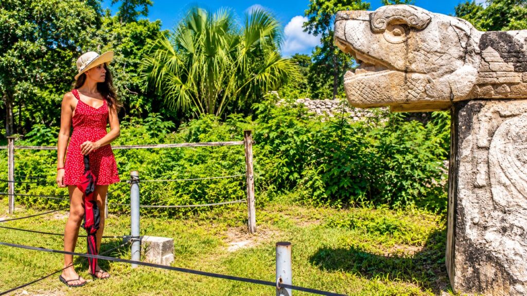 Touriste devant une sculpture de serpent maya à Chichén Itzá, au cœur de la végétation tropicale du Yucatán, Mexique.