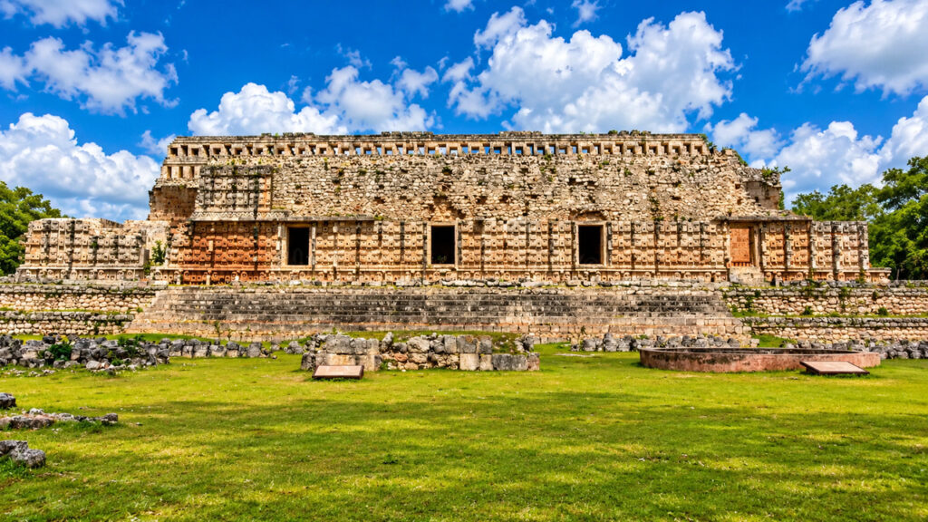 Palais maya du Yucatán au Mexique, avec une façade en pierre sculptée, une architecture de style Puuc et un ciel bleu lumineux.